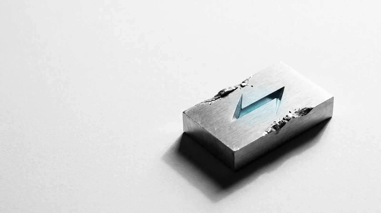 A solid aluminium block with a sharp mark struck deep into its face, the surrounding metal visibly displaced.