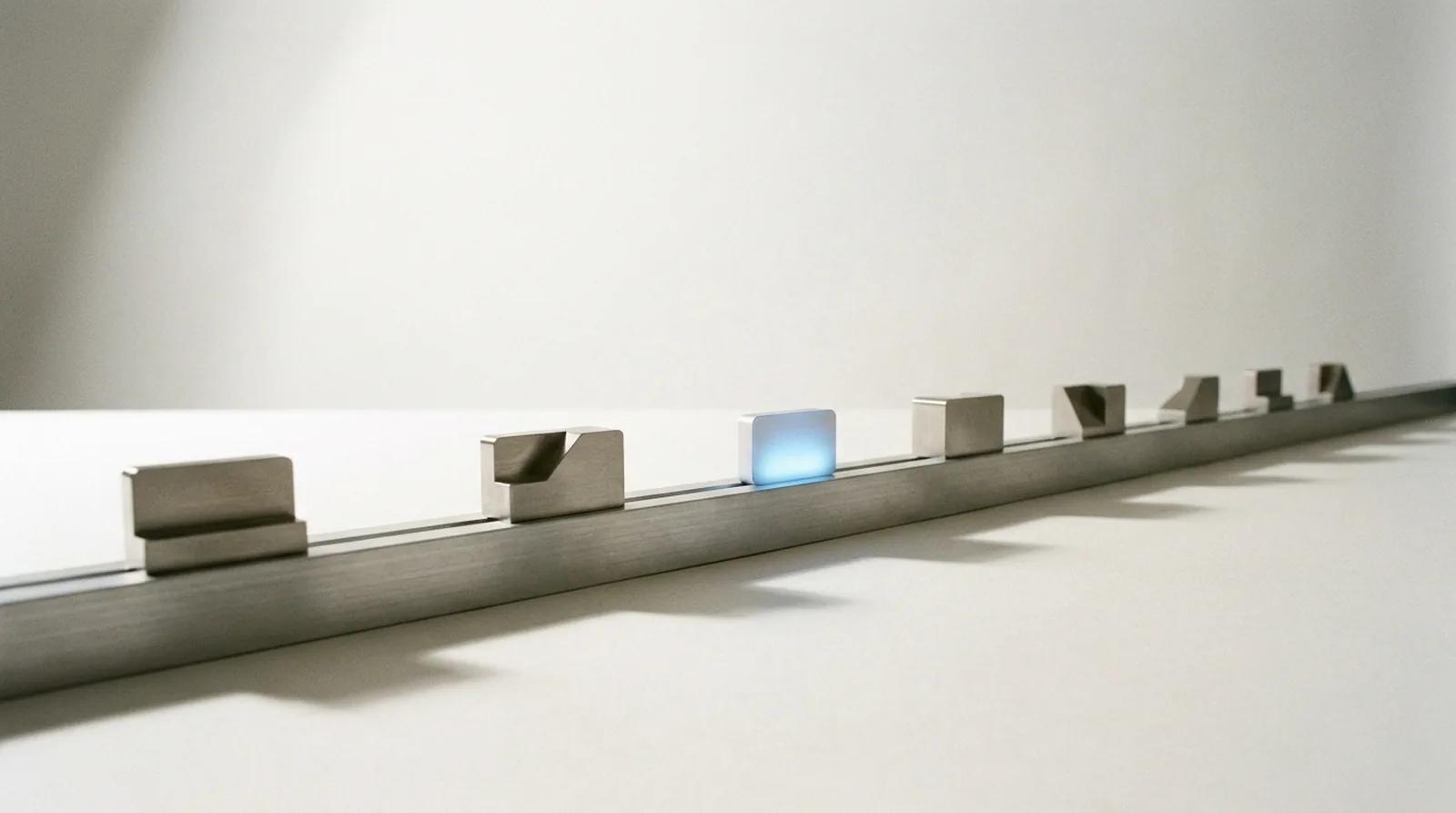 A long machined rail with seven milled stations along it, one small token lit from within resting at the third.